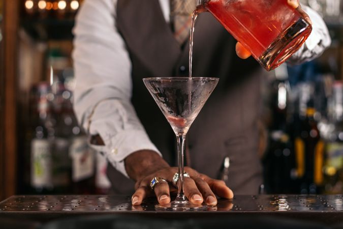 Black bartender preparing a cocktail in a traditional cocktail bar