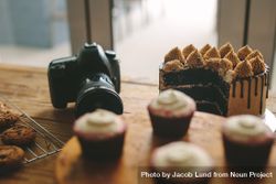 Dslr camera sitting on wooden table with desserts beogl5