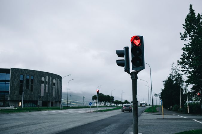 Red traffic light in heart shape against overcast sky, landscape