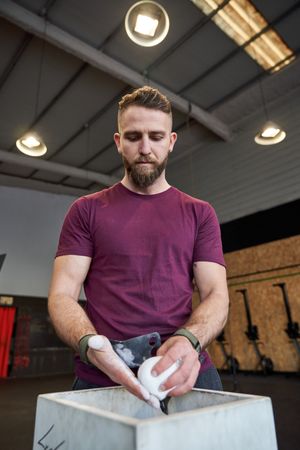 Bearded sportsman using magnesia in gym