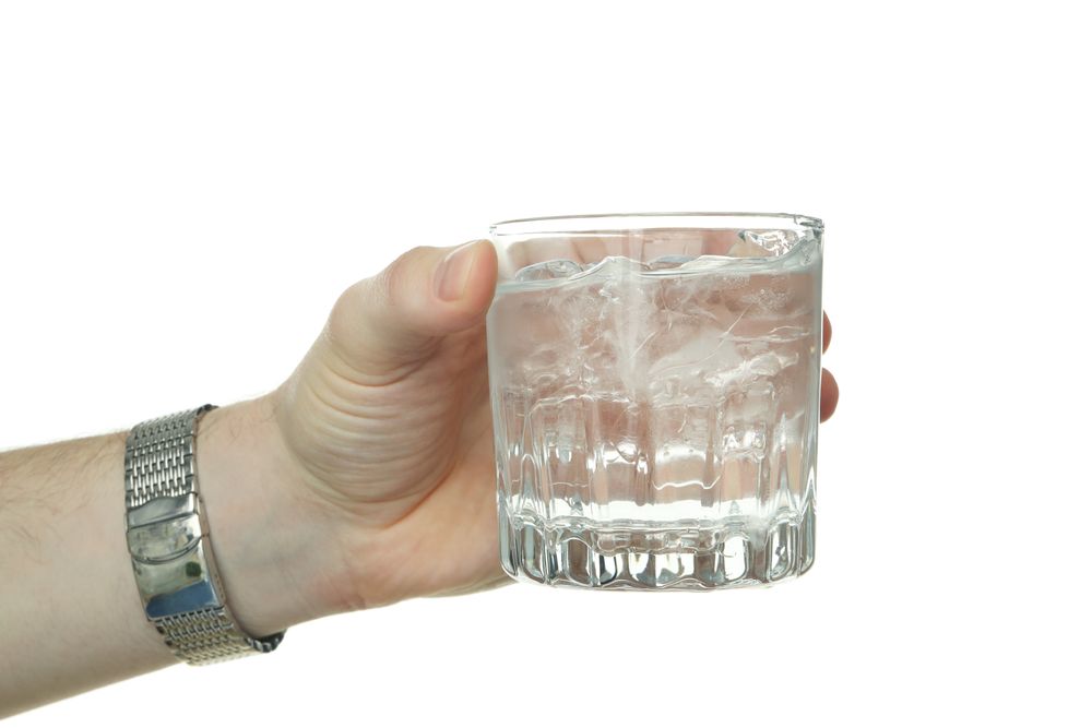 Hand holding crystal rocks glass full of water