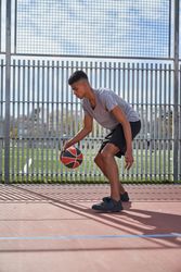 Athletic man with basketball ball training on sports ground