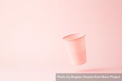 Falling pink disposable cup on pink background bGMBv5