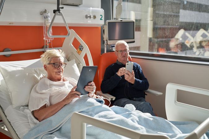 Older couple using tablet and smartphone in ward