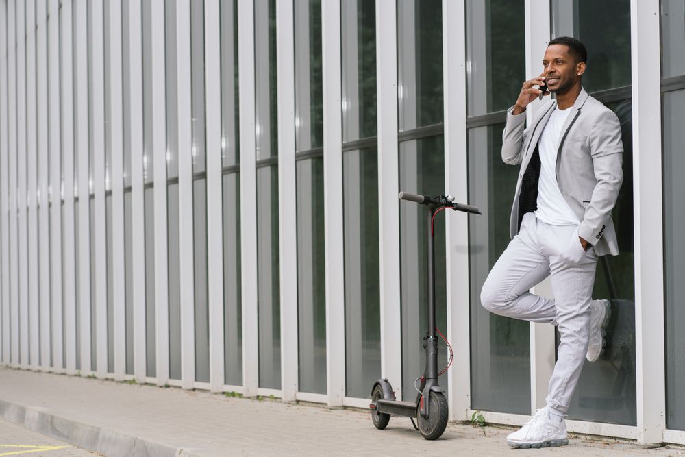 Elegant Black man talking smartphone leaning building