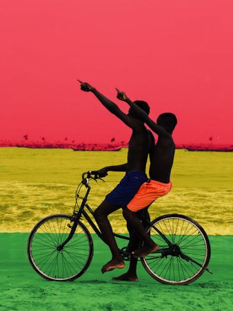 Graphic photo of two African boys riding a bicycle on the beach with Ghana flag in the background