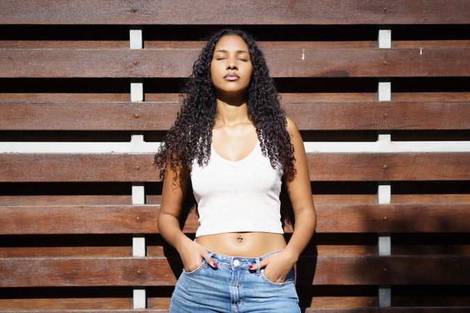 A Radiant Young Woman Posing Confidently and Gracefully Against a Charming Wooden Background