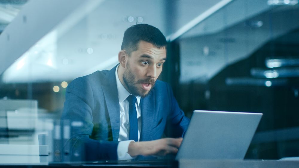 In the Office Businessman Sitting at the Desk Using Laptop Finishes Project and Wins Big.