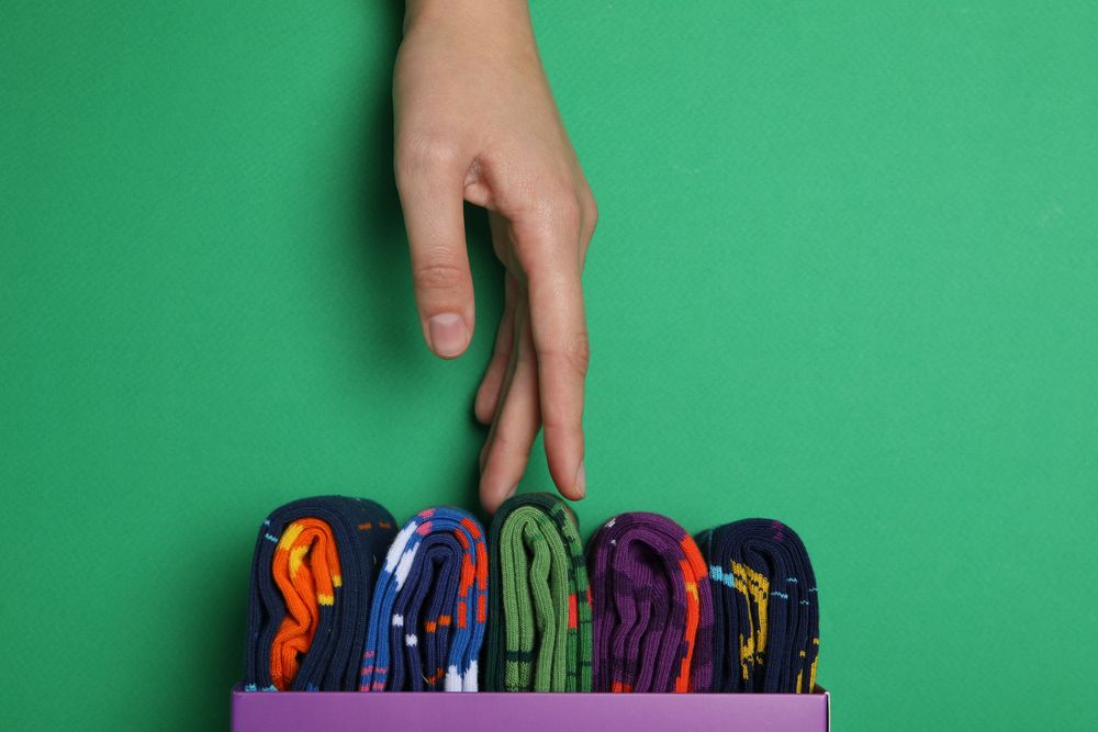 Bright socks with a print, in a box with a hand.