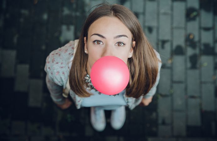 Woman looking up at camera blowing bubble gum