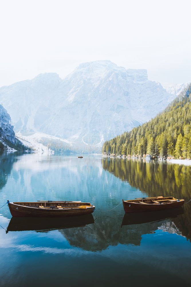 Wooden boats on lake near snow covered mountain