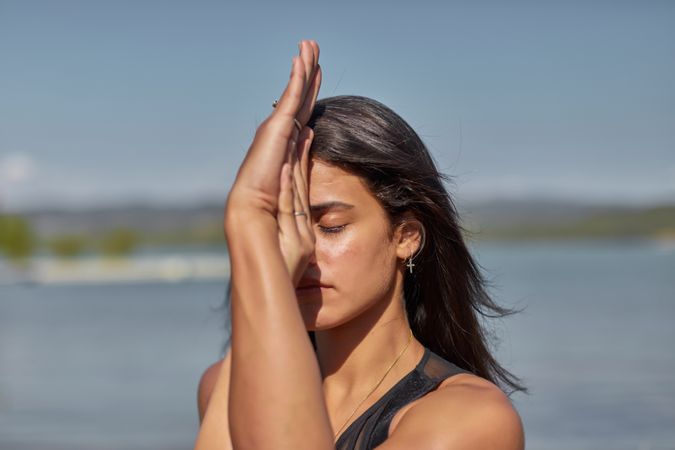 Close up of young woman with her eyes closed holding her hands in yoga pose