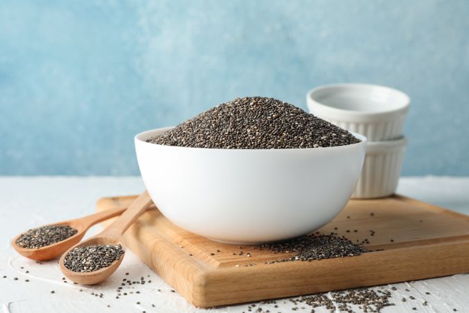 Bowl and spoons with chia on blank background, space for text