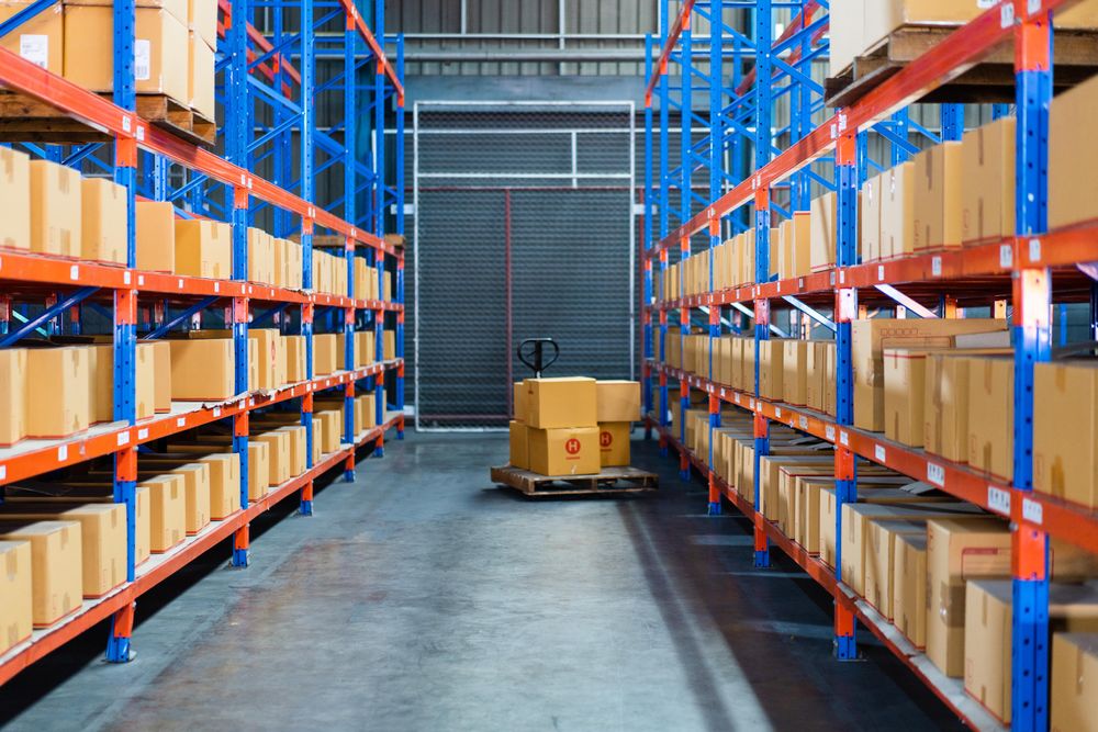 Boxes for shipping in warehouse with tall shelves and trolley