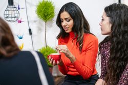 Woman stirring coffee in cafe with her friends