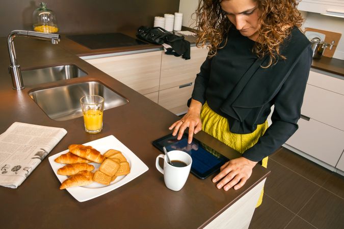 Woman reading tablet while having breakfast at home before work