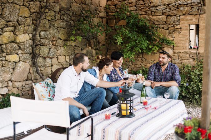 Group of laughing friends sitting together while enjoying wine at a party