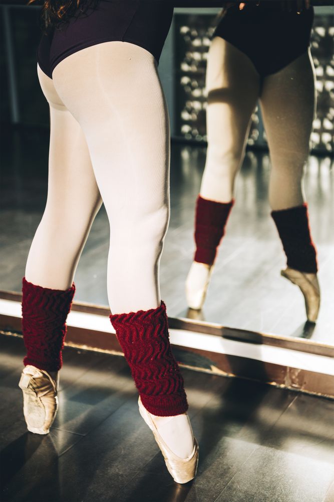 Crop anonymous dancer in pointe shoes training dance in studio.