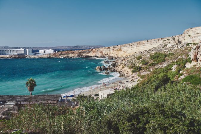 Looking down at small idyllic Maltese beach surrounded by cliffs