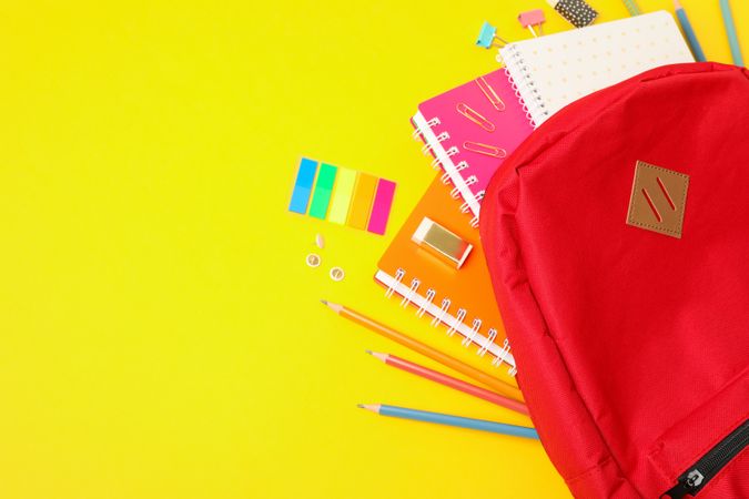 Flat lay composition with backpack and school supplies on color background
