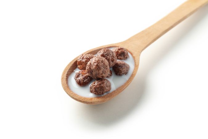 Spoon with corn balls and milk isolated on plain background