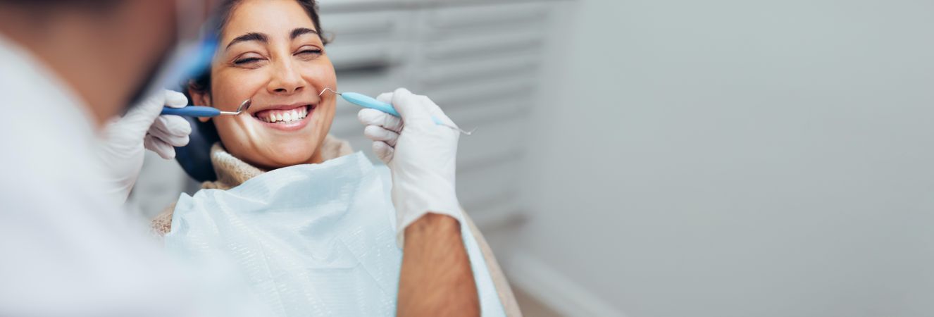 Woman reclined in chair and smiling up at dentist