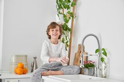 Smiling boy washing hands with soap in morning
