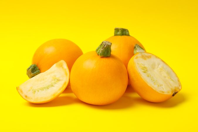 Bunch of round zucchini on yellow background
