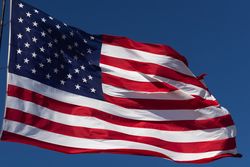 American Flag Waving In Wind Against a Deep Blue Sky.