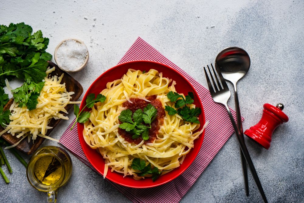 Fettuccine pasta with cheese & tomato sauce on counter with copy space