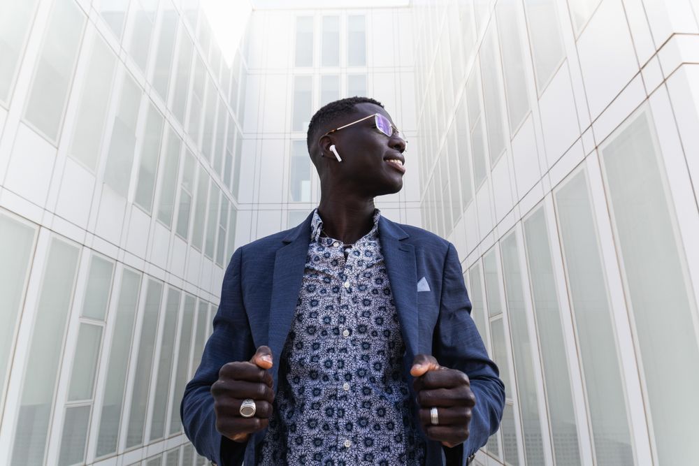 Content Black businessman listening to music in earbuds in city