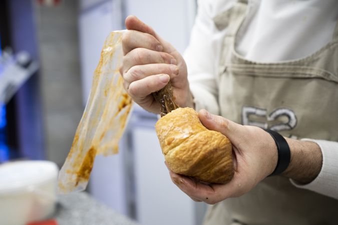 Confectioner pouring chocolate filling into croissant