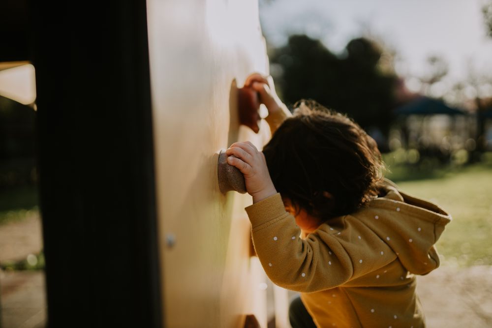 A young child on a rock climbing wall outside