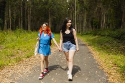 A couple of young lesbian women walk hand in hand along a rural path during a nature excursion in Galicia