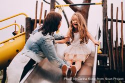 Woman and girl play on a slide of a playground k4MP15