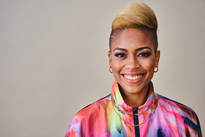 Studio shot of joyful Black woman in bold 80s windbreaker jacket