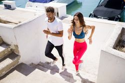 Male and female running on stairs near waterfront
