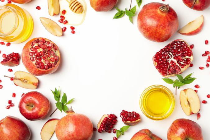 Looking down at circle of fresh apples, pomegranate and honey with copy space
