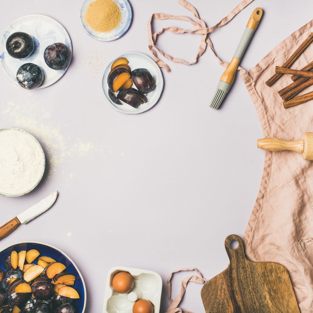Baking ingredients and tools, plums, pastry brush, cinnamon, eggs on pastel background, square crop