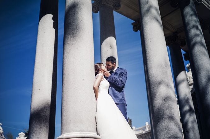 Newlyweds kissing near columns