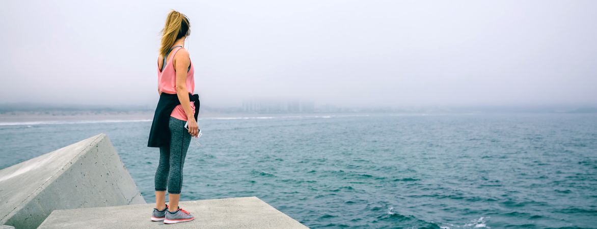 Young woman on concrete block watching the sea