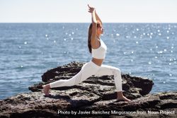 Woman wearing sport clothes and stretching on coastal rocks 488aq4