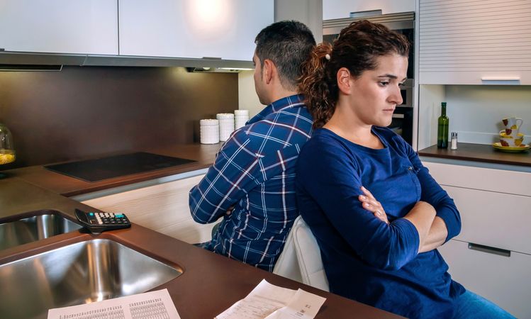 Couple sitting in kitchen angry with each other