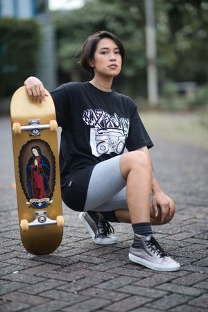Woman crouching beside skateboard