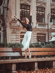 Gentle ballerina dancing on street bench