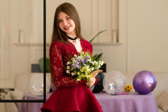 Teen girl in red lace dress holding bouquet of flowers