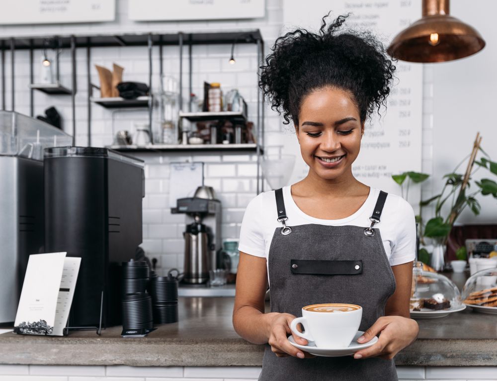 Happy barista looking down at cappuccino