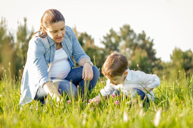 Pregnant mother and son picking flowers in a field