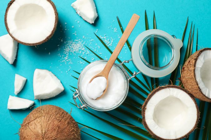 Coconut, palm branch and cosmetic on turquoise background. Tropical fruit