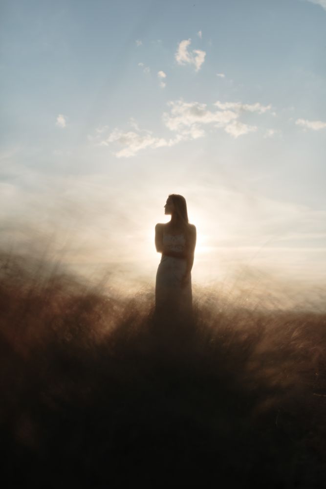Young woman standing in an open field looking to the side